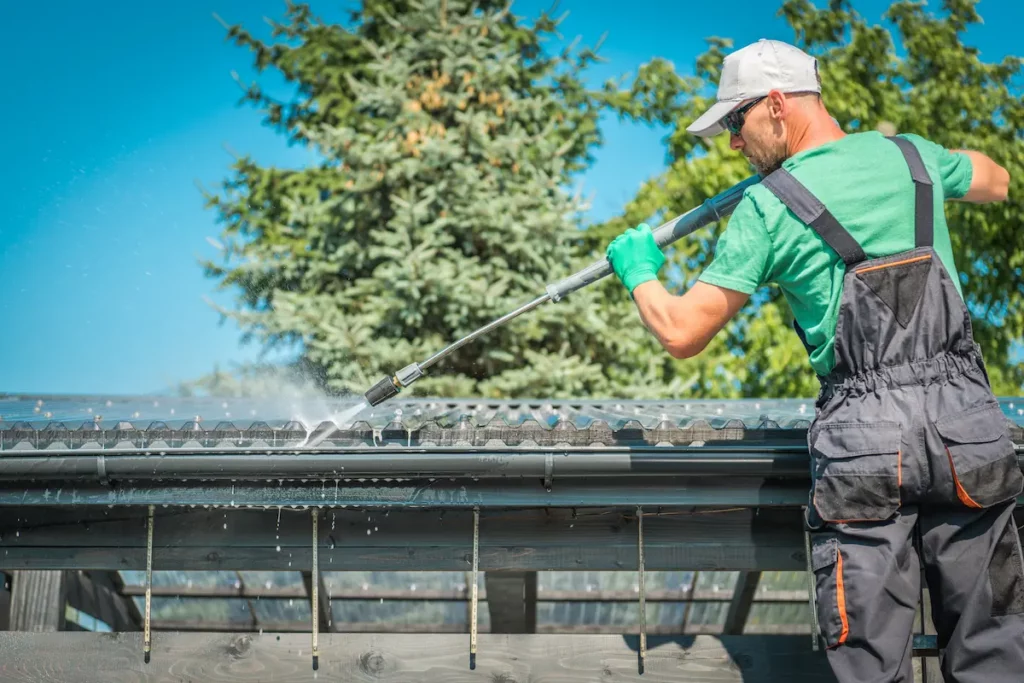 image of man cleaning a gutter with a high pressure hose