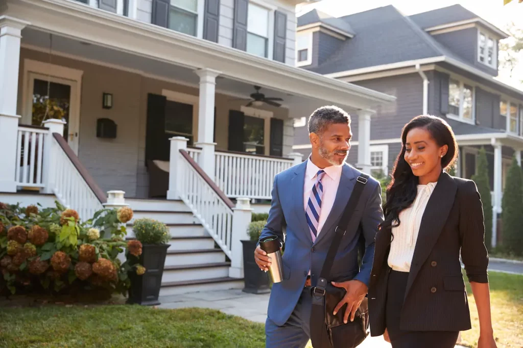 Image if black couple in real estate industry walking away from residential house.