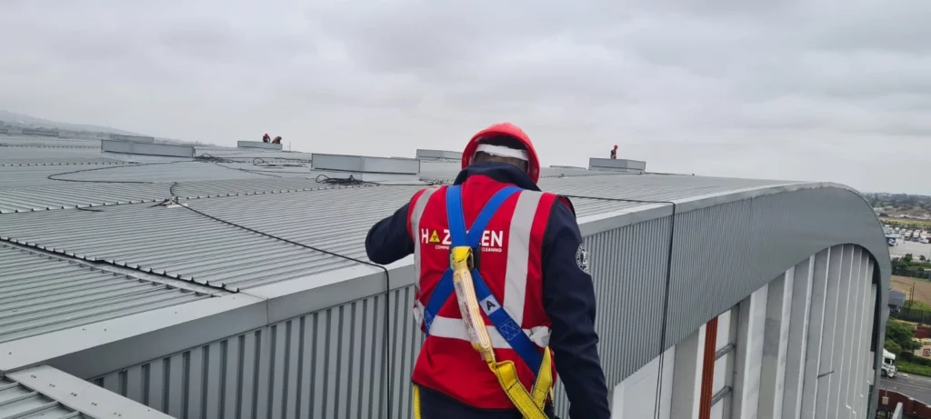 Image of Haztech worker wearing a red Haztech vest and red hard hat, on a building roof.